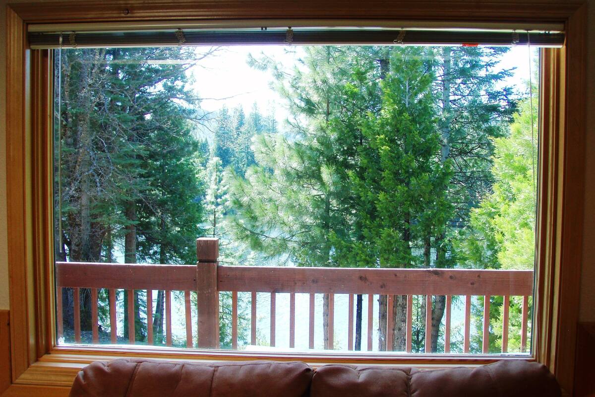 A window with a view of a wooden deck and trees.