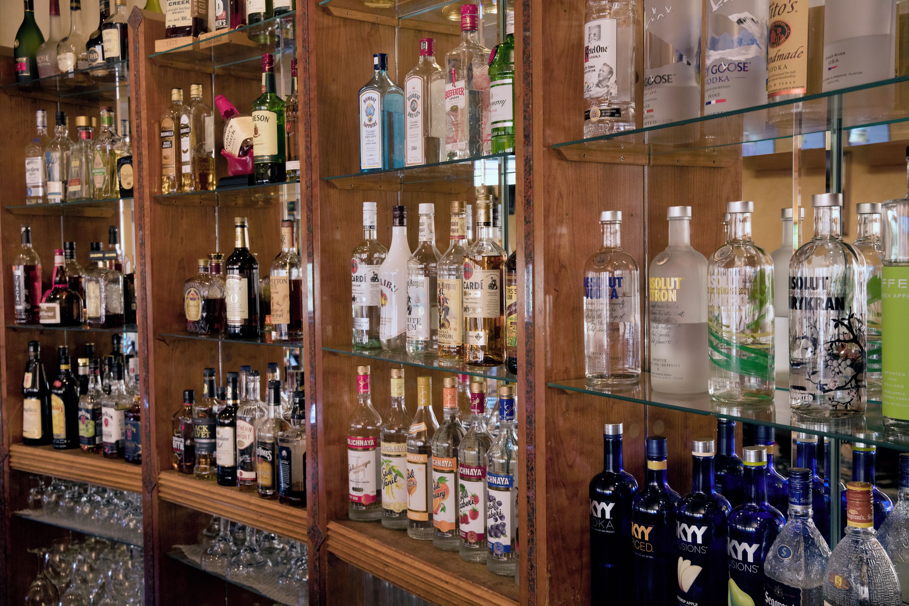 A bar with multiple shelves stocked with various liquor bottles and glasses.