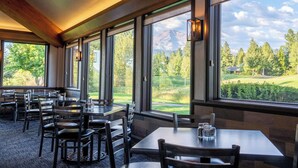 Restaurante con amplios ventanales que ofrecen vistas a la montaña. Mesas y sillas dispuestas para comer.