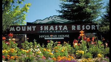 Schild für das Mount Shasta Resort, mit Bergpanorama und einem Garten voller bunter Blumen im Vordergrund.