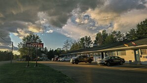 Un motel avec une enseigne, des voitures garées et un bâtiment doté d’un toit en pente.