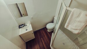 Une petite salle de bain comprenant des toilettes, un lavabo, un miroir et une douche.