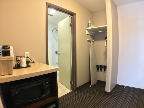 A hotel bathroom with a shower, a sink, a microwave, and a coffee maker on the counter.