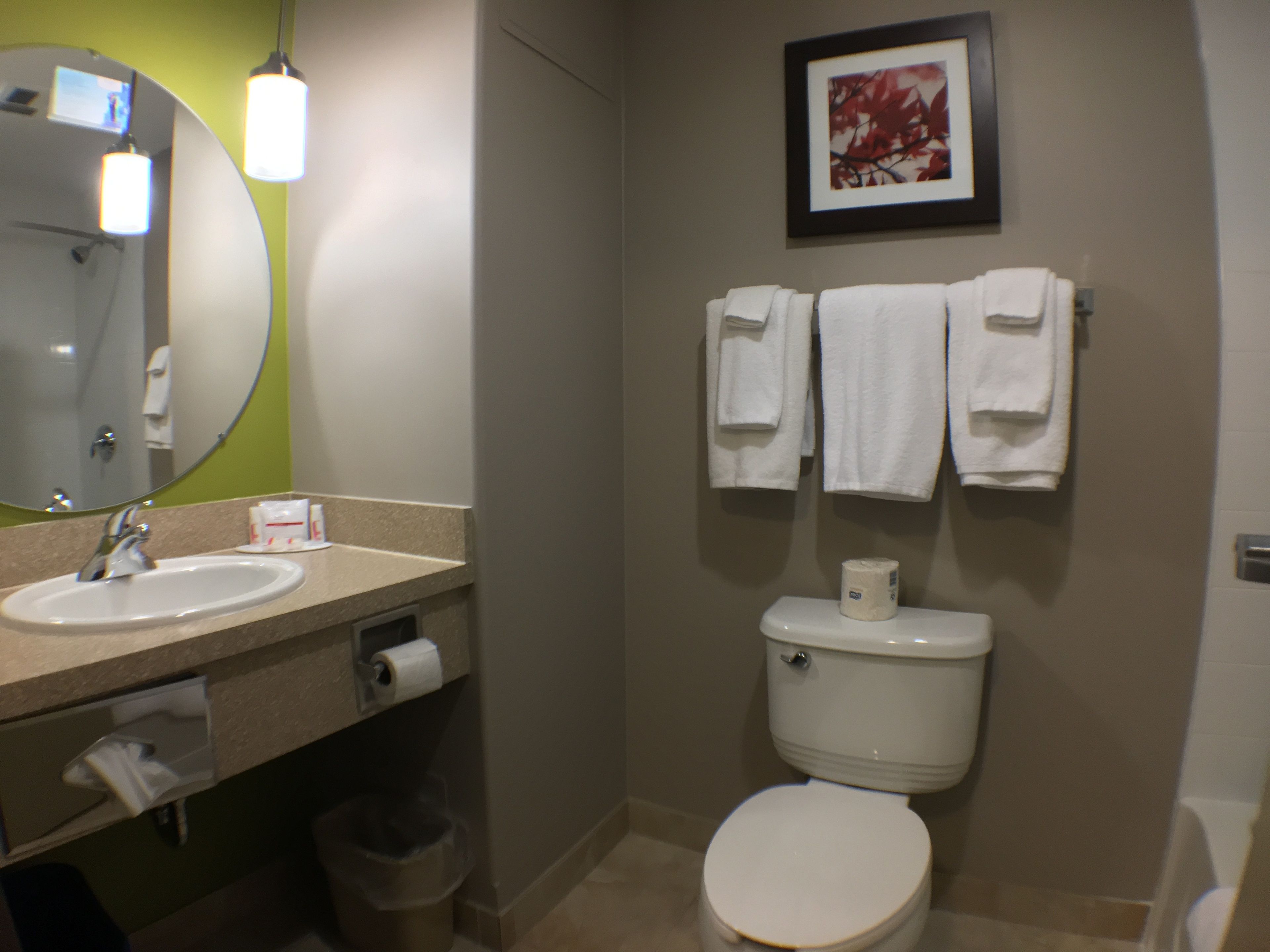 A bathroom with a sink, mirror, toilet, and towels.