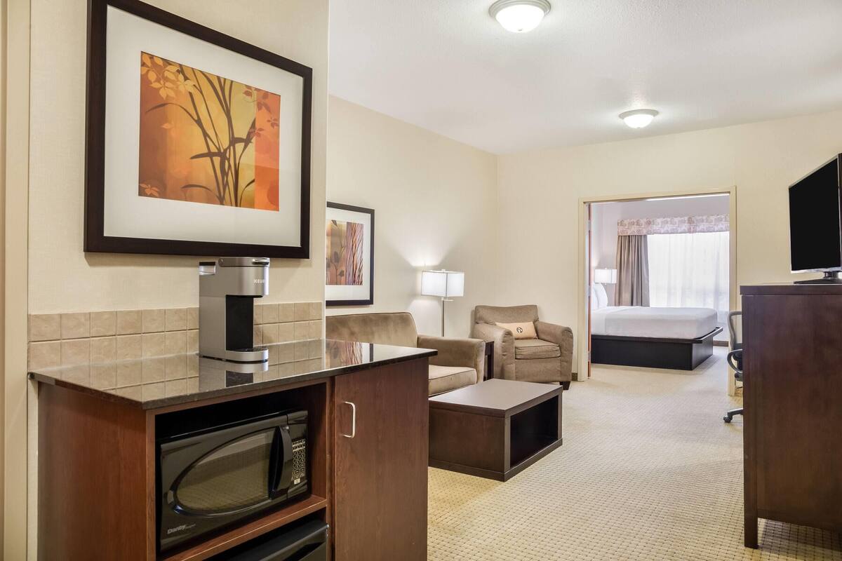 Une chambre d’hôtel équipée d’une kitchenette, d’un lit, d’une télévision et d’un tableau encadré au mur.
