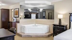 Un baño de hotel con un espejo grande, una bañera, un tocador con una lámpara y un armario de madera.