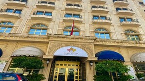Un hotel de varios pisos con una entrada destacada, balcones y una bandera.