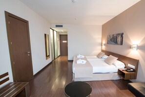 Habitación de hotel con cama, mesita de noche, lámpara y un cuadro en la pared.