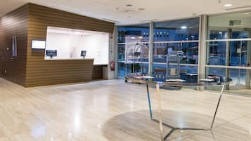 A reception area with a wooden reception desk, a glass display table, and a view of the outside through large windows.