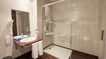 A modern bathroom with a glass-enclosed shower, a sink with a mirror, and a towel rack.