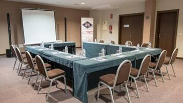 A conference room with a long table, chairs, a projector screen, and a banner.