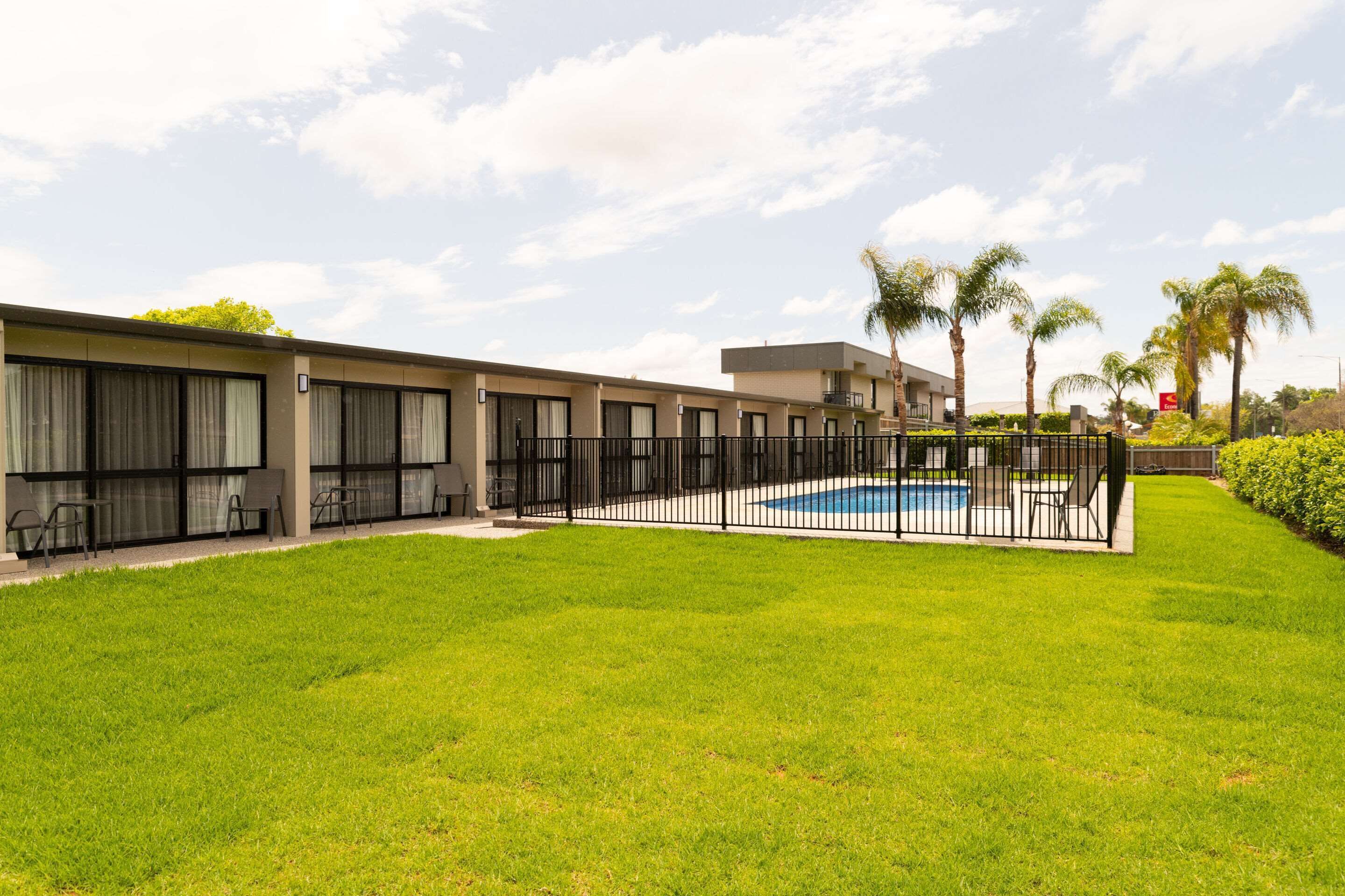 Un hotel con piscina, mobiliario exterior y palmeras.