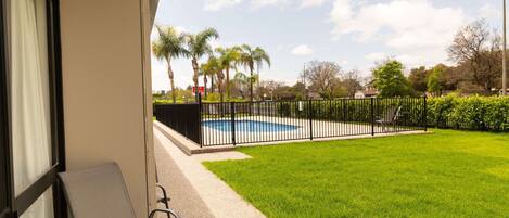 A balcony with a chair, a pool, and a fence.