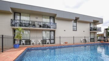 Un edificio moderno con piscina, balcones y un patio amurallado.