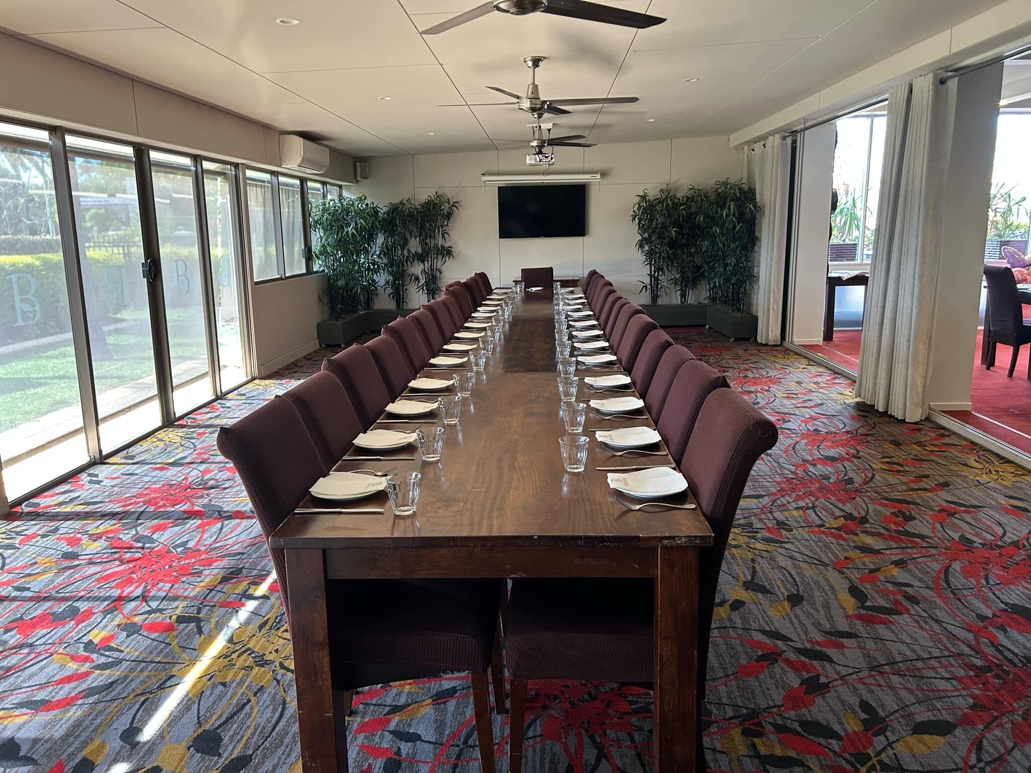 A conference room with a long table, chairs, and a ceiling fan.