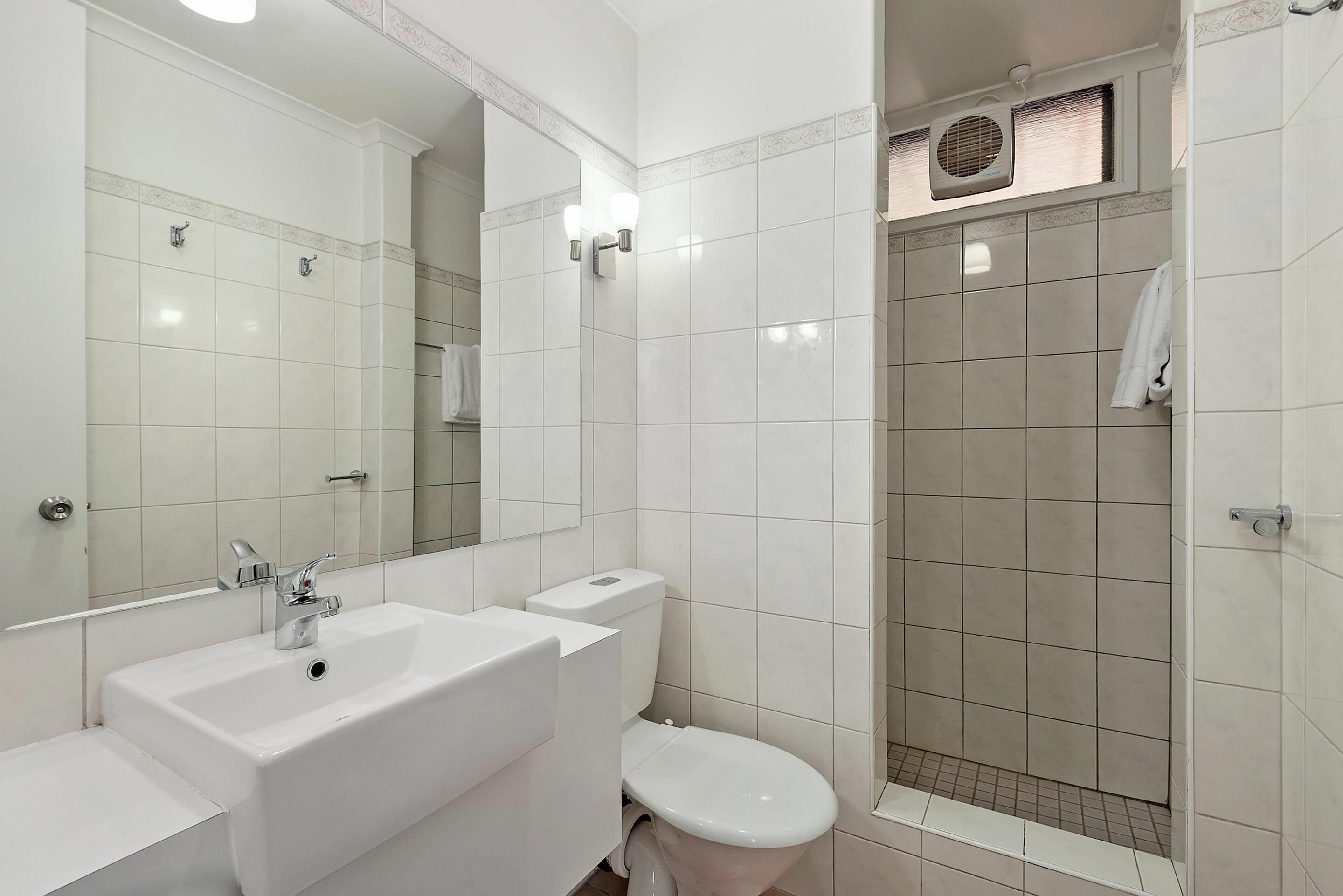 A modern bathroom with a white sink, toilet, and shower area.