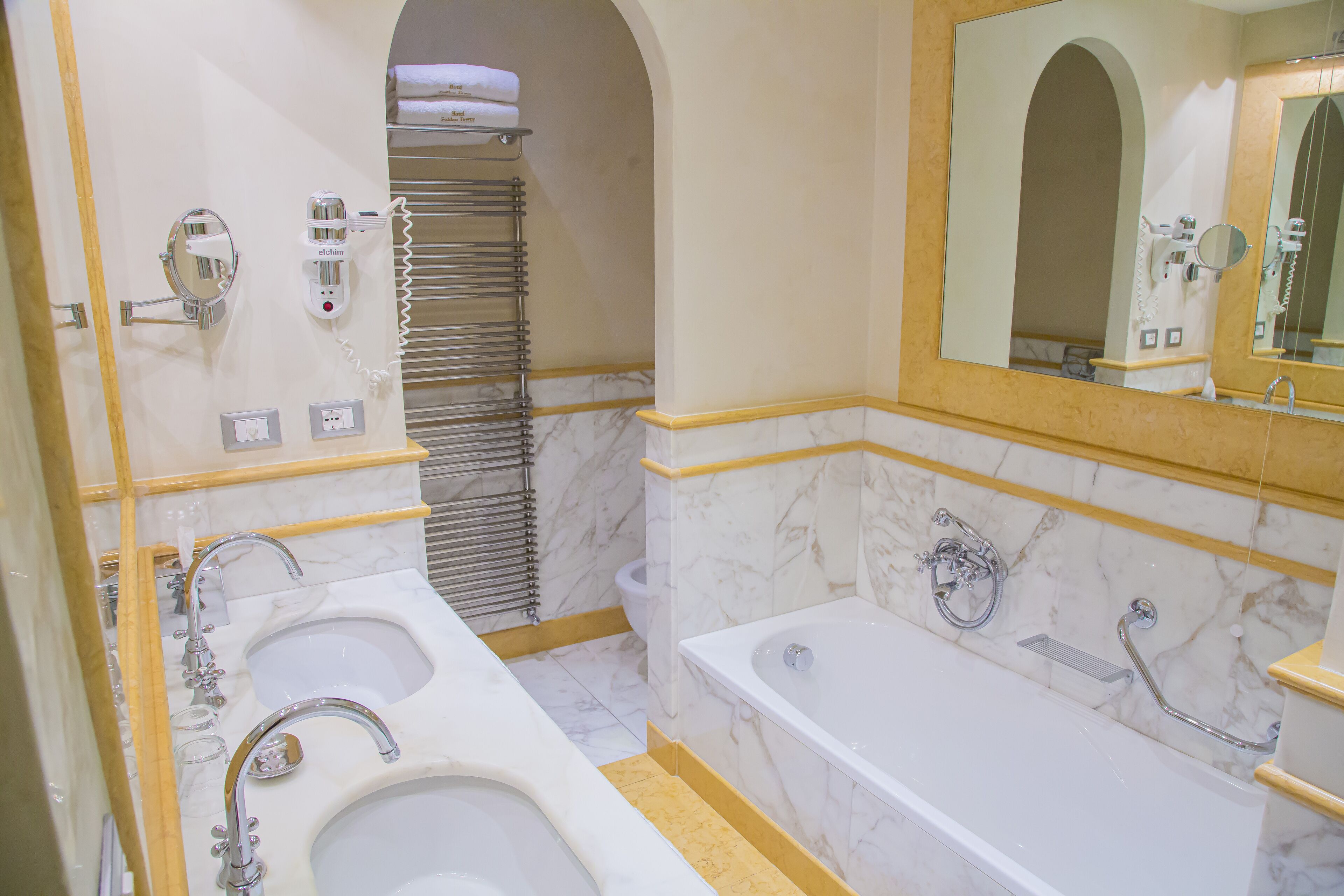 Un bagno con due lavandini, una vasca, un portasciugamani e uno specchio.