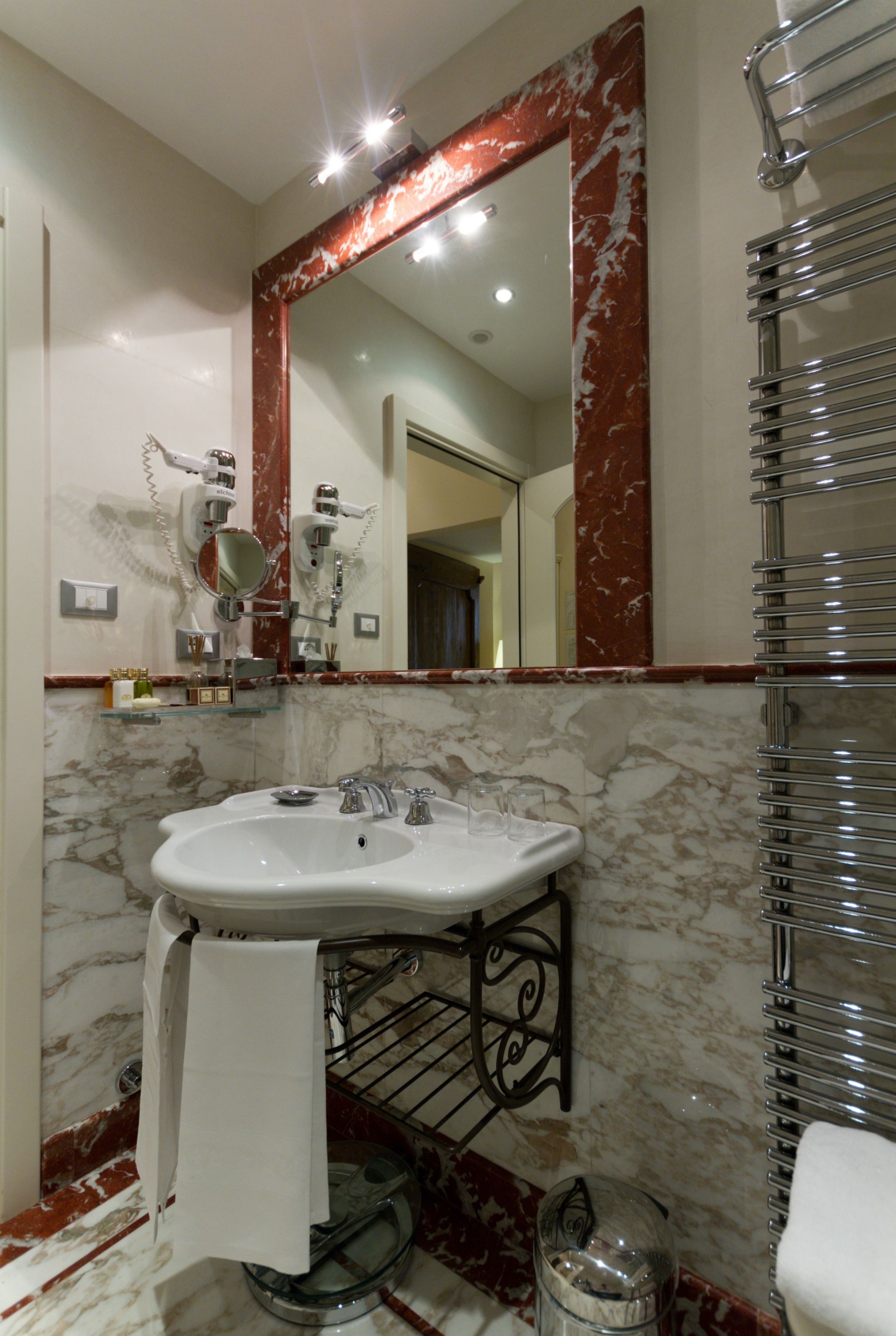 Un bagno con un lavabo in marmo, uno specchio grande e un porta asciugamani.