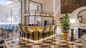 A bar area with a marble wall, a checkered floor, and a large painting on the wall.