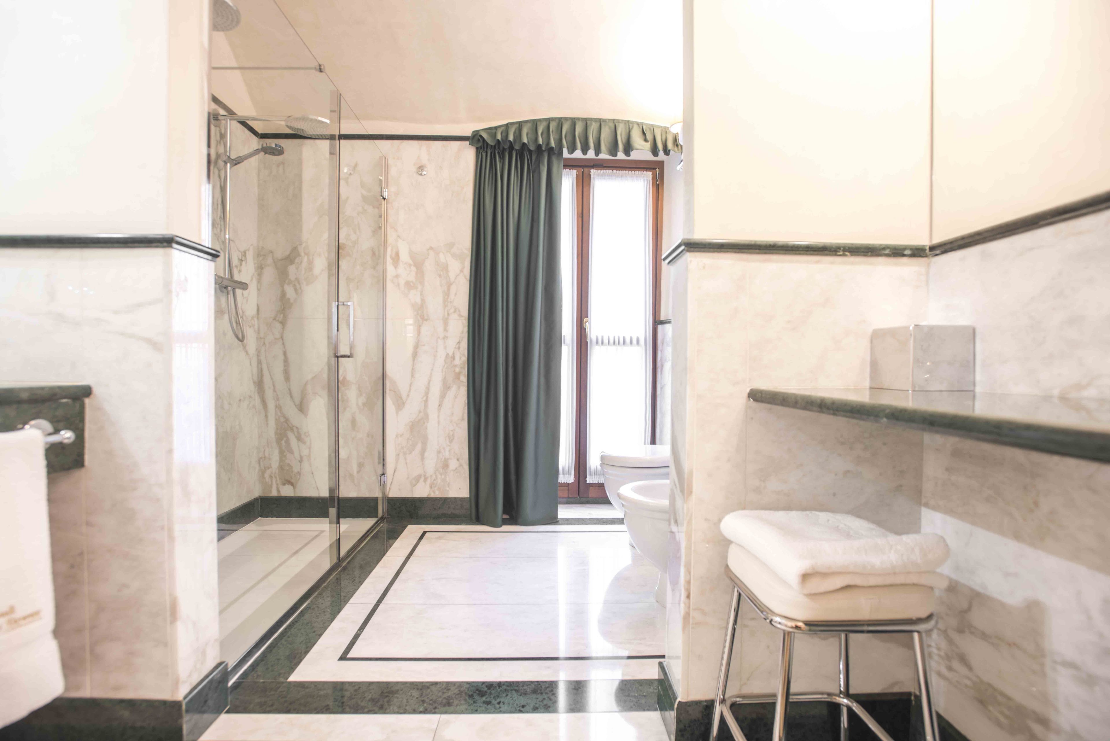 A bathroom with a glass-enclosed shower, a toilet, and a sink.
