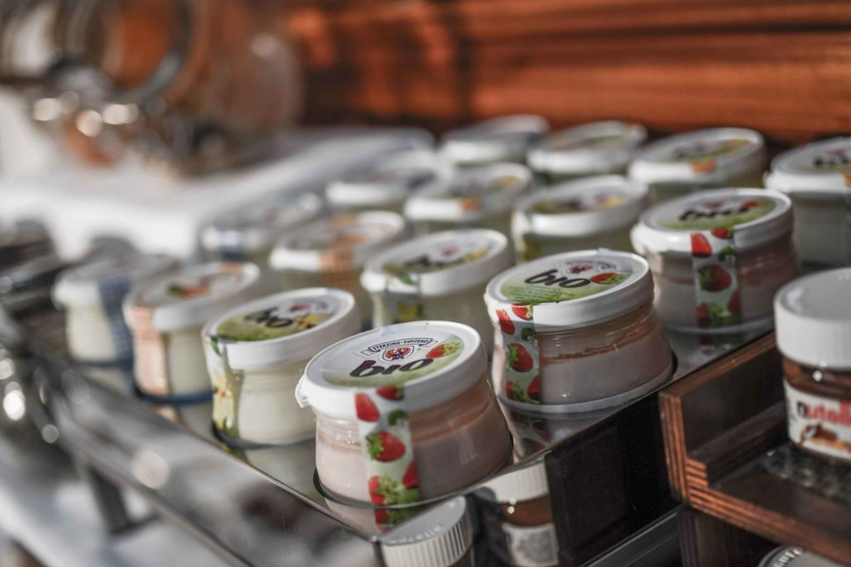 A variety of jars with labels, likely containing food items, arranged on a reflective surface.