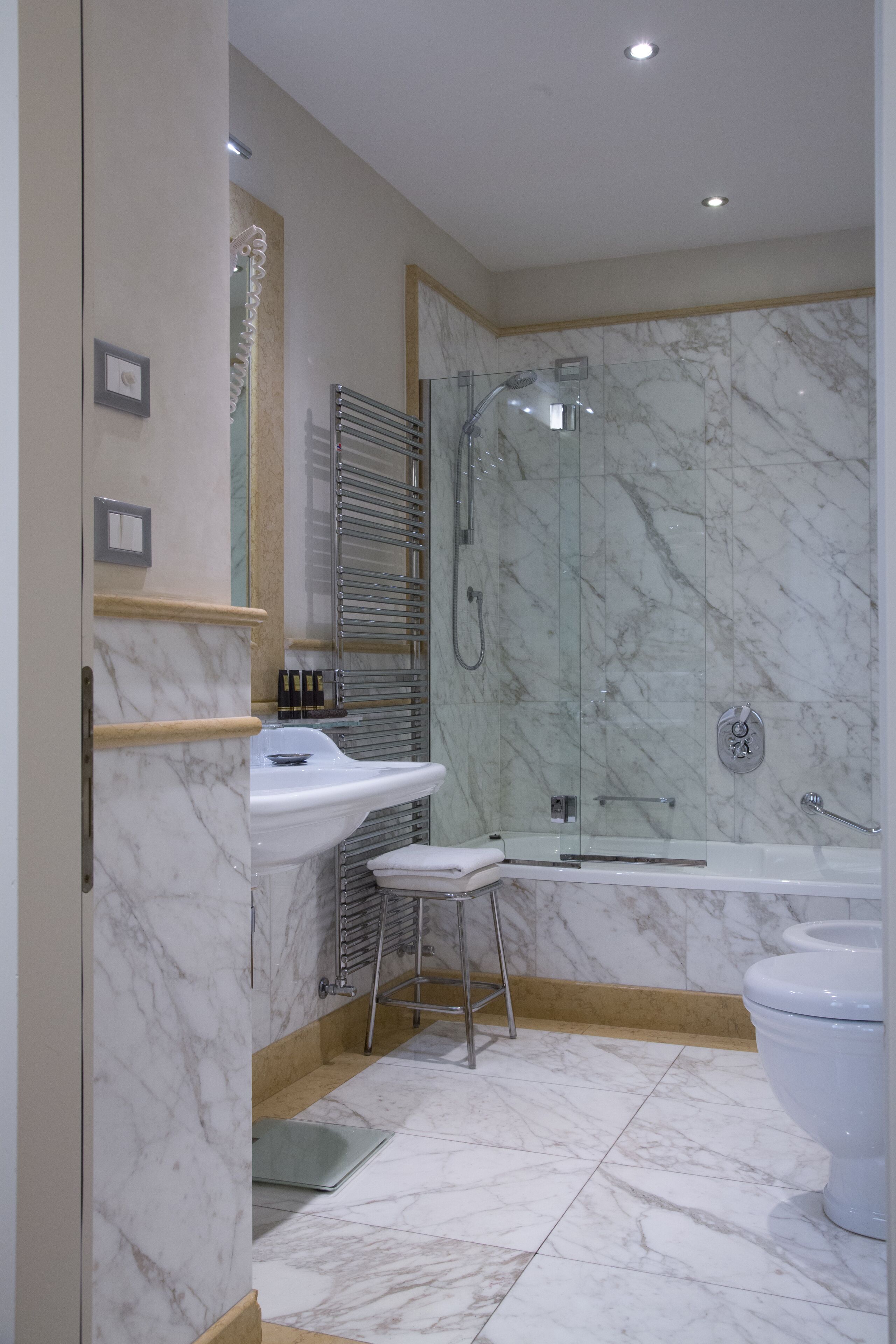 Un baño moderno con ducha envuelta en vidrio, un lavamanos blanco y un inodoro.