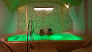 A hot tub with two people, surrounded by a tiled wall with a "GOLDEN" sign.