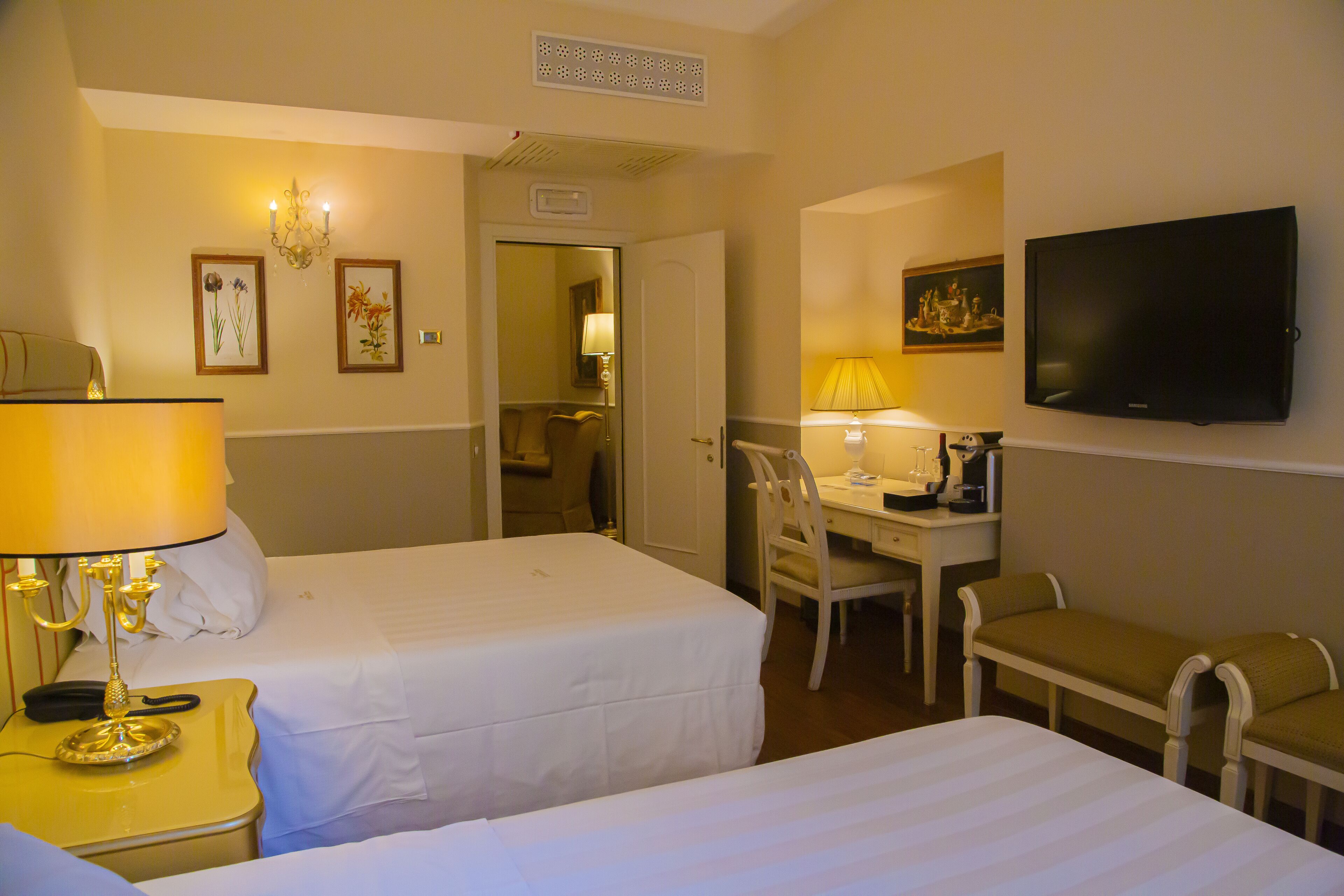 Una habitación de hotel con dos camas, un escritorio, una silla, un televisor y una lámpara.