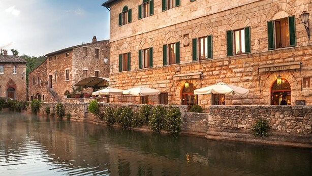 Un edificio de piedra con un restaurante llamado "Ristorante Bar Enoteca" junto al agua.