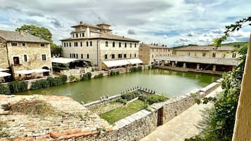 Uma cidade histórica com edifícios de pedra, um canal central e uma muralha de pedra com estátuas.