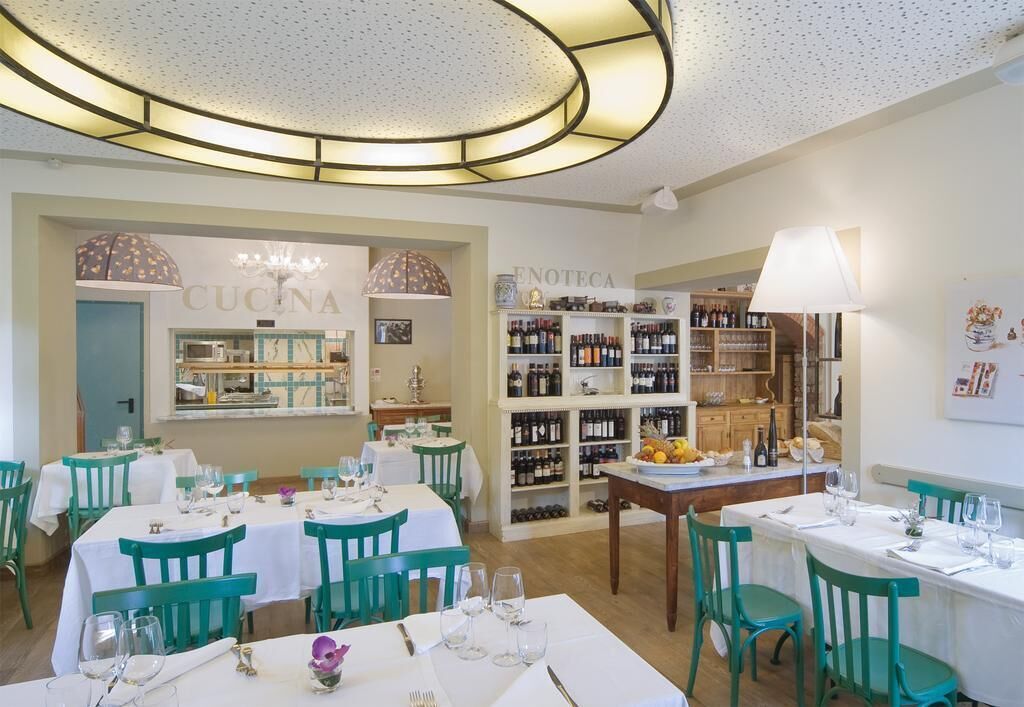 A restaurant with multiple tables and chairs, a wine rack, and a chandelier.