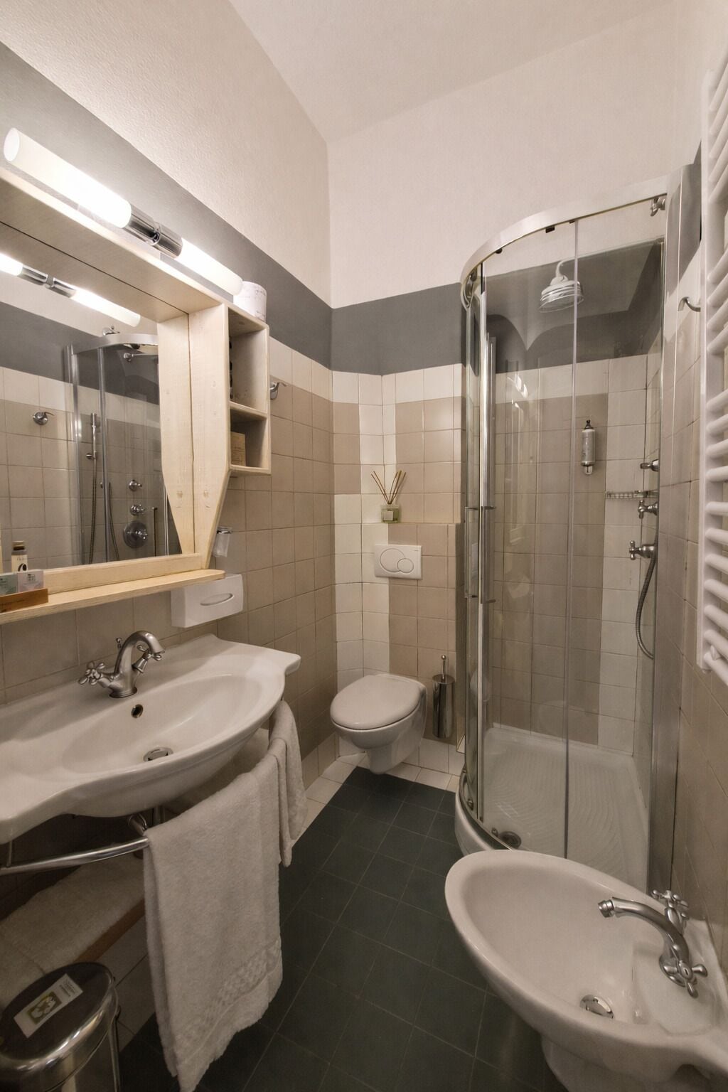 A modern bathroom with two sinks, a toilet, and a glass-enclosed shower.