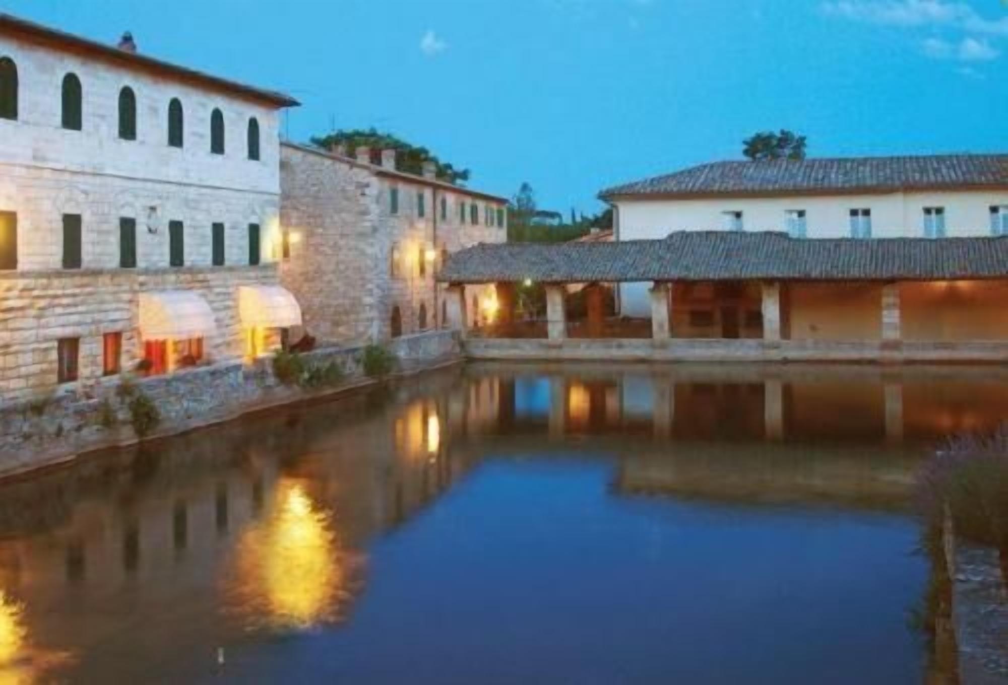 Un edificio histórico con muros de piedra y un patio que refleja una piscina.