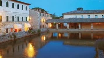 A historic building with stone walls and a courtyard reflecting a pool.
