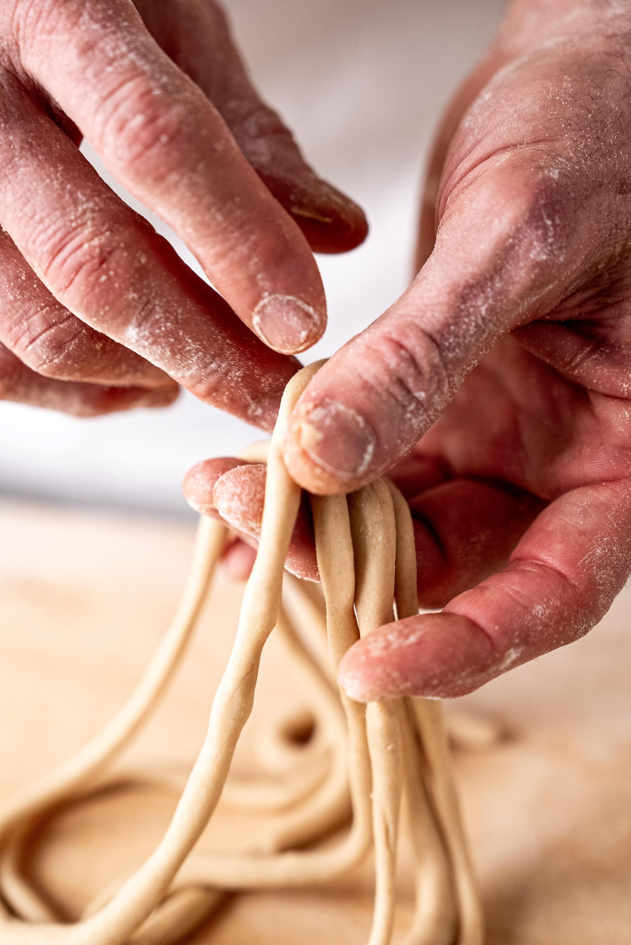 Manos moldeando masa para hacer pasta.