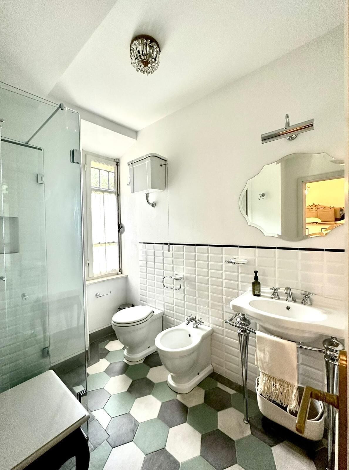 A bathroom with a glass shower, a toilet, a bidet, a sink, and a mirror.
