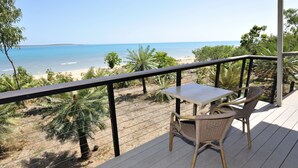A balcony with a table and chairs overlooking a beach.