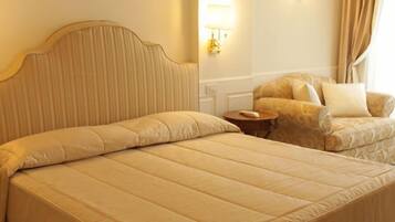 Una habitación de hotel con una cama grande, una silla, una mesita de noche con teléfono y lámparas de pared.