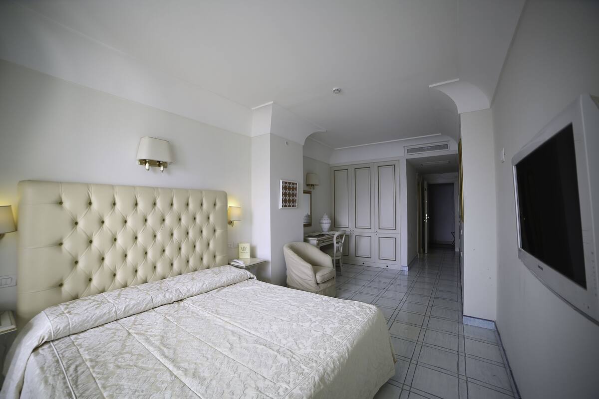 A hotel room with a large bed, a desk, and a TV.