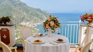 Une table ronde recouverte d’une nappe blanche, deux chaises, un vase de fleurs et des assiettes remplies de nourriture.