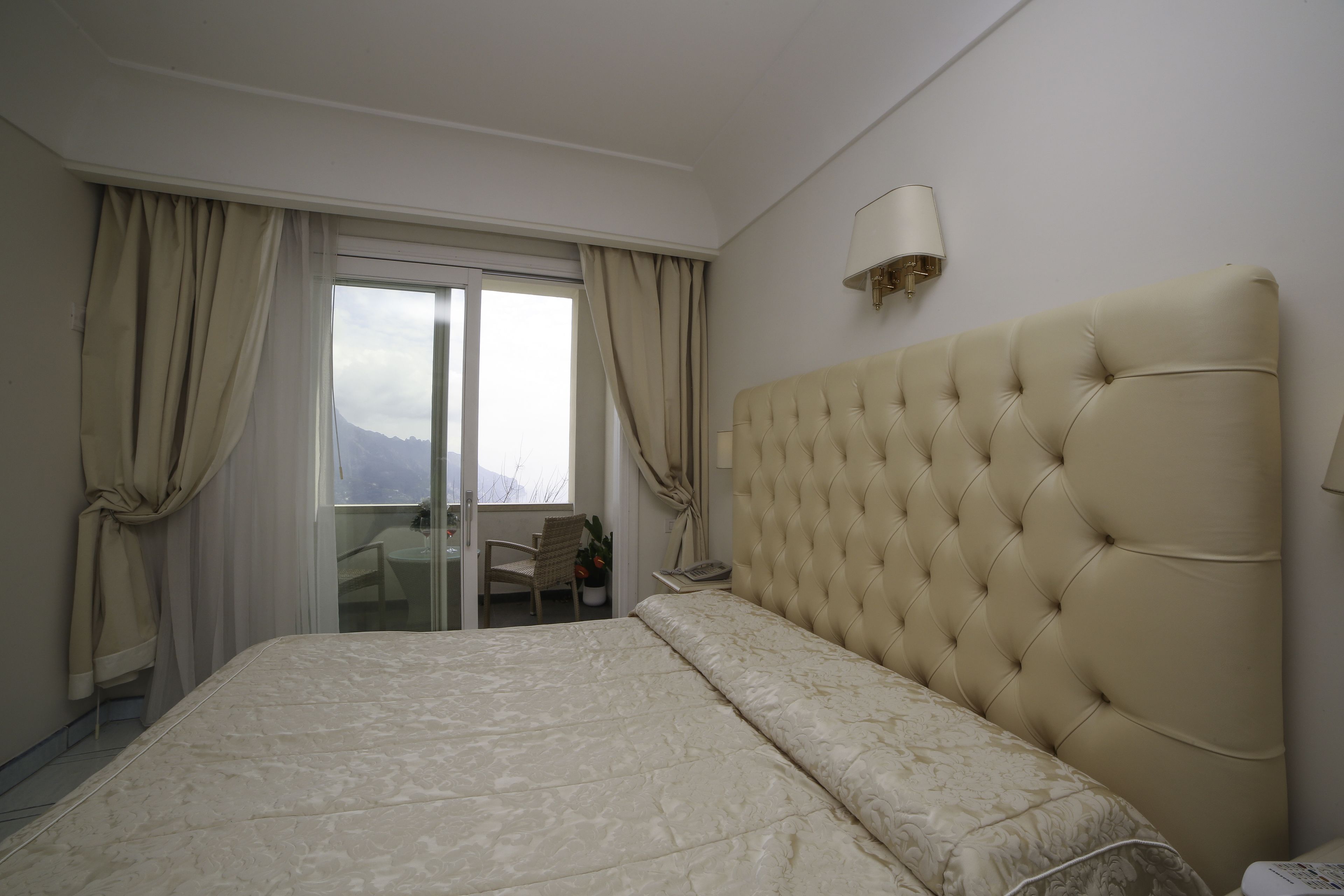 Ein Hotelzimmer mit einem großen Bett, einer Schiebetür zum Balkon und einer Wandleuchte.