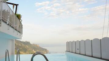 Una piscina al aire libre, sillones reclinables de piscina