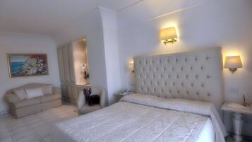 Un dormitorio con una cama grande, un sofá, un escritorio y un cuadro en la pared.