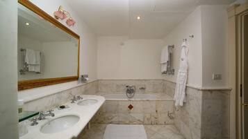 A bathroom with two sinks, a bathtub, and a large mirror.