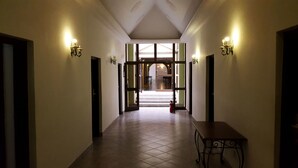 Un pasillo con una mesa, sillas, un extintor y una puerta que da a otra habitación.
