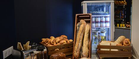 A bakery display with various breads and pastries, a toaster, and a refrigerator in the background.