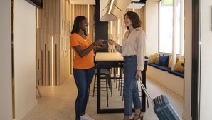 Two people in a modern hotel lobby with a seating area and a large mirror. - Ibis Styles Paris Opéra Lafayette (Paris)