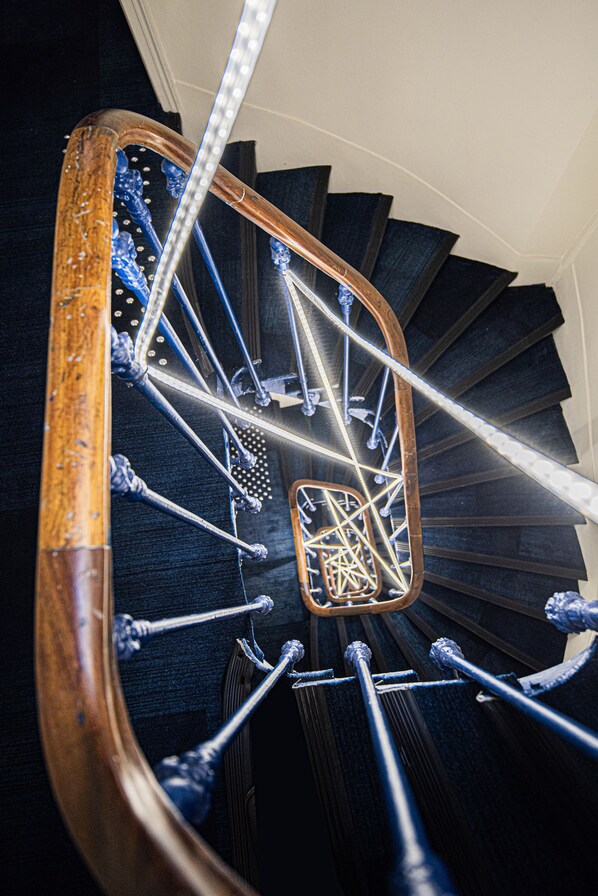 A spiral staircase with wooden handrails and metal balusters. - Ibis Styles Paris Opéra Lafayette (Paris)