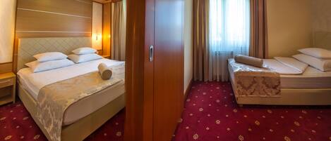 Una camera d'albergo con un letto grande, un letto più piccolo, un armadio e un tappeto rosso.