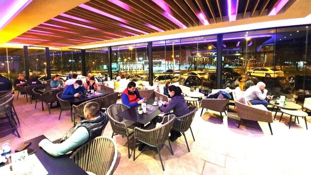 An indoor dining area with tables and chairs, large windows, and a modern ceiling design. - Cezar Hotel (Banja Luka)